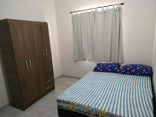 een slaapkamer met een bed en een houten kast bij Casa em Unamar 3 Cabo Frio RJ in Tamoios