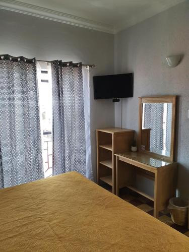 um quarto com uma cama, uma televisão e uma janela em Hotel Rivera em Oaxaca de Juárez