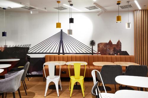 a restaurant with tables and chairs with yellow chairs at Holiday Inn Express - Warsaw - The HUB by IHG in Warsaw