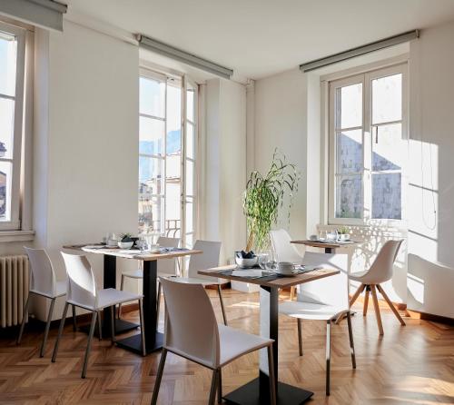 a dining room with tables and chairs and windows at Lainez Rooms & Suites in Trento