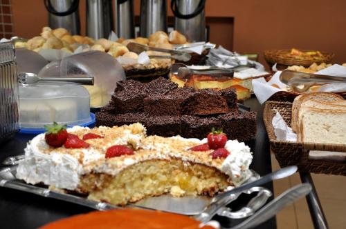 a table filled with different types of cakes and bread at Hotel Carolina Plaza in Uberaba