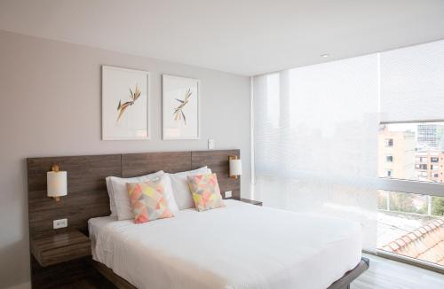 a white bedroom with a large bed and a window at Urban Heights Bogota in Bogotá