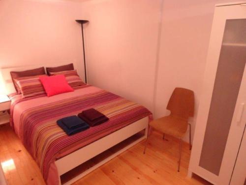 een slaapkamer met een bed met een stoel en rode kussens bij Lisbon City Centre Apartment in Lissabon