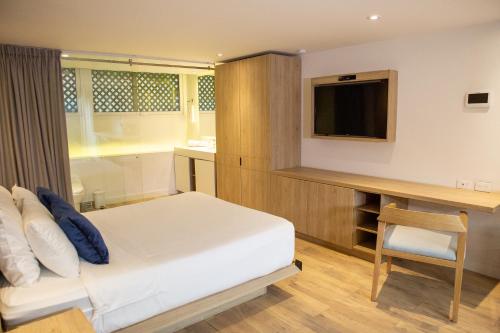 a bedroom with a bed and a desk and a television at Urban Heights Bogota in Bogotá