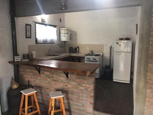 cocina con encimera, fogones y nevera en El Campito casa frente al río en Villa Carlos Paz