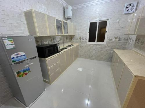 uma cozinha com um frigorífico e um micro-ondas em ابيات ميرا em Abha