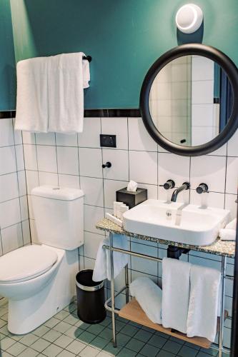 a bathroom with a toilet and a sink and a mirror at Stay at Hotel Steyne in Sydney