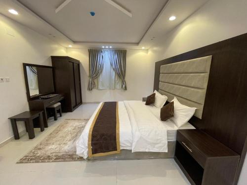 una grande camera da letto con un grande letto e una scrivania di ابيات ميرا a Abha