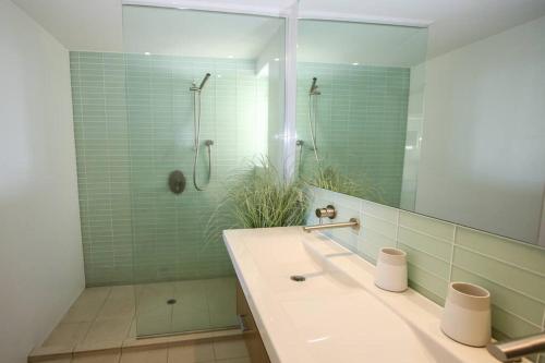 a bathroom with a sink and a shower with a mirror at Waves 8 - Beachfront with pool in Point Lookout