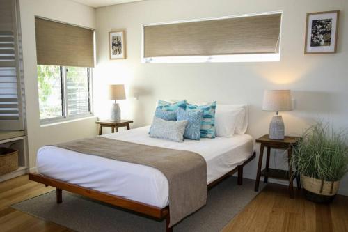 a bedroom with a large white bed with blue pillows at Waves 8 - Beachfront with pool in Point Lookout