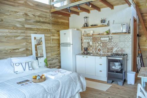 a bedroom with a bed and a kitchen with a refrigerator at Loft Casa no Farol in Laguna