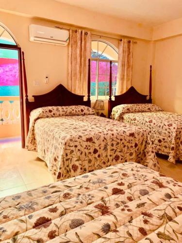 a hotel room with two beds and two windows at Solet's Paradise Negril in Negril
