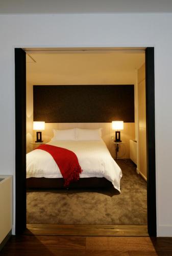 a bedroom with a large white bed with a red blanket at The Ridge Hakuba Hotel & Apartments in Hakuba