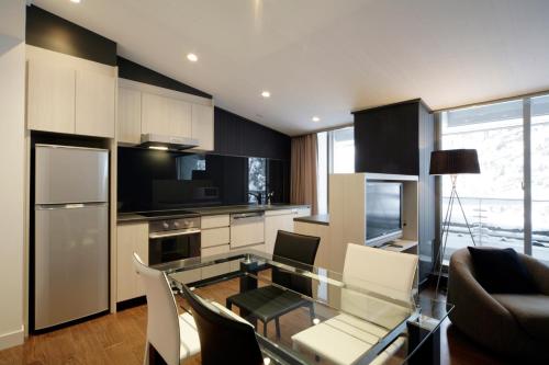 a kitchen with a glass table and some chairs at The Ridge Hakuba Hotel & Apartments in Hakuba