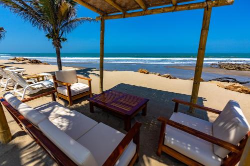 a group of chairs and a table on the beach at Hotel Punta Camarón Bungalows & Suites in Zorritos