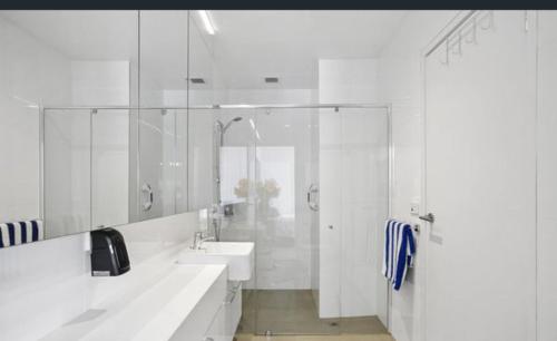 a white bathroom with two sinks and a shower at Luxury Beach Front Appartment in Rosebud