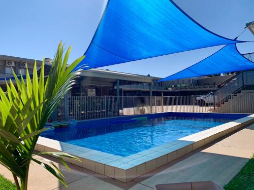 a swimming pool with a blue umbrella over it at Central Motel Mildura in Mildura