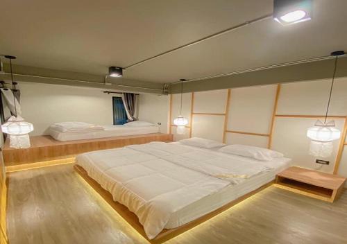 a bedroom with a large white bed and two lamps at Little One in Chiang Rai