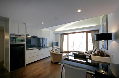 a kitchen and living room with a couch and a table at The Ridge Hakuba Hotel & Apartments in Hakuba