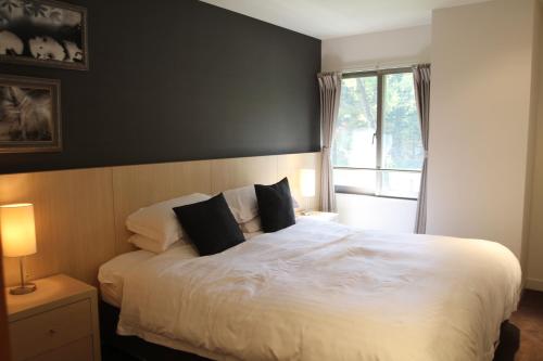 a bedroom with a large white bed with two pillows at The Ridge Hakuba Hotel & Apartments in Hakuba