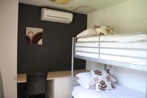 a room with two bunk beds and a desk at The Ridge Hakuba Hotel & Apartments in Hakuba
