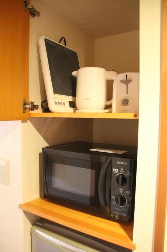 a microwave and other appliances on shelves in a kitchen at The Ridge Hakuba Hotel & Apartments in Hakuba