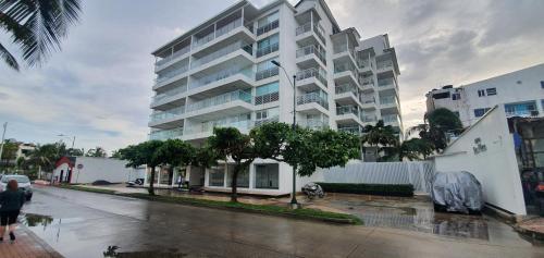 a large white building on a wet street with trees at Edificio Sea View - Apartamento 303 B in San Andrés