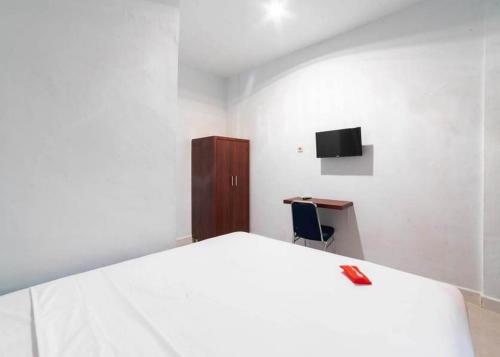 1 dormitorio con 1 cama blanca grande y escritorio en KoolKost near Wisata Purwahamba Indah Tegal, en Tegal