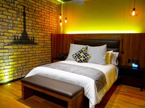 a bedroom with a bed and a brick wall at Cadillac Hotel Boutique in Mexico City