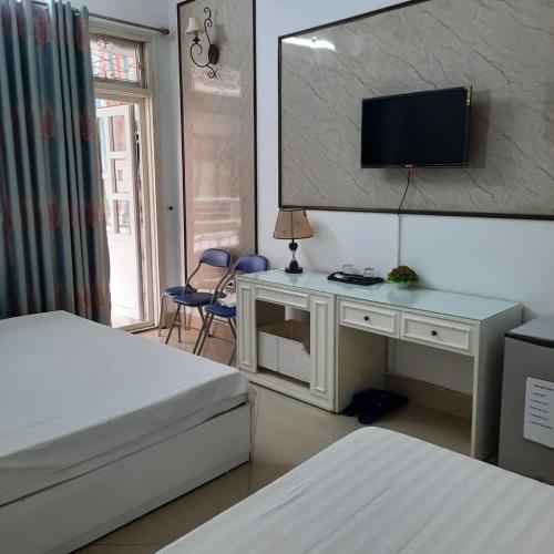 a bedroom with two beds and a desk with a television at Hanoi Carina Hotel in Hanoi