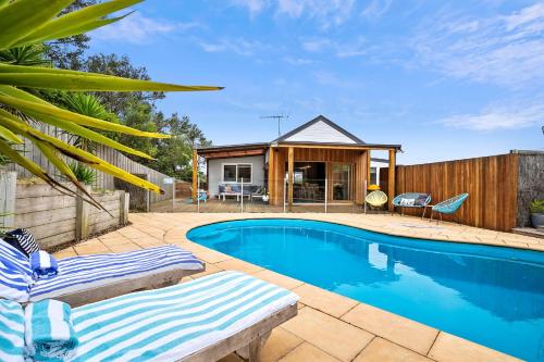 a swimming pool with two lounge chairs and a house at Paws Up Poolside in Rye