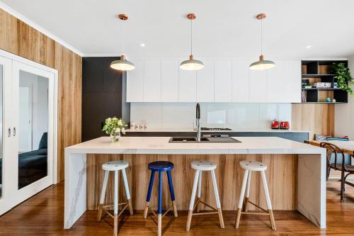 a kitchen with a large white island with bar stools at Paws Up Poolside in Rye