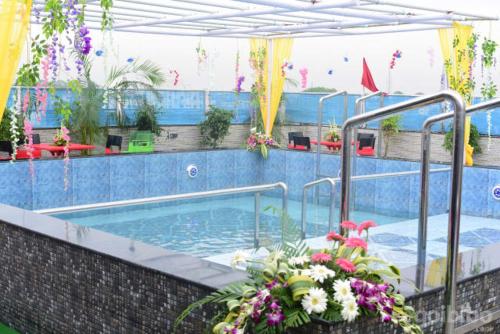 a large swimming pool with flowers in a building at Hotel Madhuvan by TravelkartOnline in Dhanbād