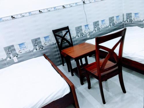 Nhà nghỉ Đế Vương في Thu Dau Mot: طاولة وكراسي في غرفة بسريرين