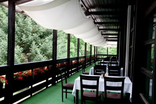 a restaurant with white tables and chairs and windows at Everest Hotel in Etropole