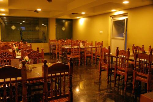 uma sala de jantar com mesas e cadeiras em um restaurante em ACK Palacce Inn em Yercaud