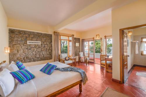 1 dormitorio con cama y pared de piedra en Windermere Estate, en Munnar