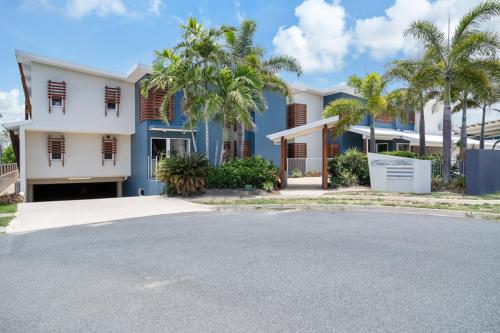 a blue and white house with palm trees and a street at Marina Beach Holiday Home in Cremorne