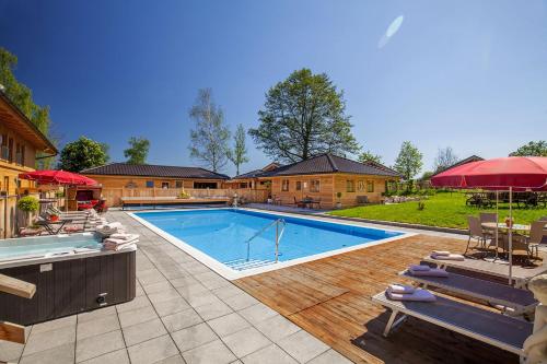 una piscina en un patio con sillas y sombrillas en Hotel Rupertihof, en Ainring