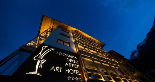 a building with a sign on the side of it at Locanda degli Artisti Art Hotel in Canazei