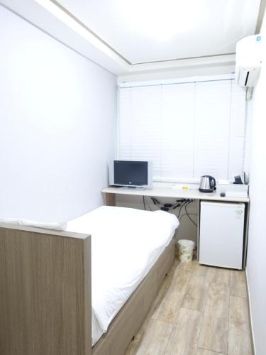 1 dormitorio con 1 cama y escritorio con ordenador en Gangnam Suncity Guesthouse, en Seúl