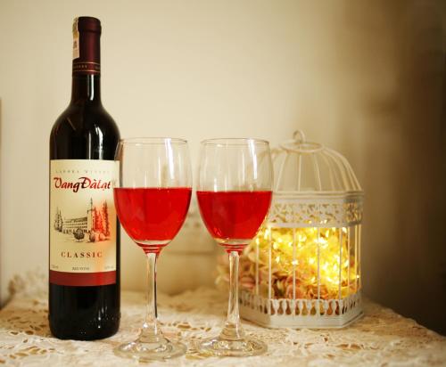 two glasses of red wine next to a bottle of wine at Hotel Như ý Biên Hòa in Bien Hoa