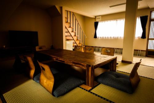 Biker's Inn Onomichi 自転車の宿おのみち في أونوميتشي: غرفة طعام مع طاولة وكراسي خشبية