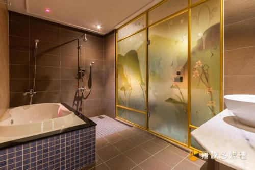 een badkamer met een douche, een bad en een wastafel bij Zheng Yi Hotel & Motel I in Taitung