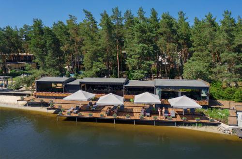 a restaurant with tables and white umbrellas on the water at GOOD ZONE Hotel in Peschanka