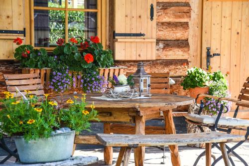 a wooden table and chairs with flowers on a patio at Almchalet Alpenflora in Werfenweng