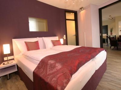 a bedroom with a large bed with a red blanket at Apart Hotel Seenelke in Wilhelmshaven