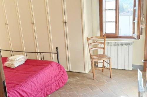 1 dormitorio con 1 cama, 1 silla y 1 ventana en Appartamento rustico con vista en Montelupo Fiorentino