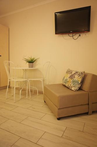 a living room with a couch and a table and a tv at Bait Alfa Kibbutz Country Lodging in Bet Alfa