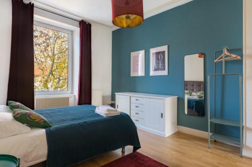 Schlafzimmer mit blauen Wänden, einem Bett und einem Fenster in der Unterkunft Travel Homes - The Wooden, Spacieux & bon quartier in Mulhouse